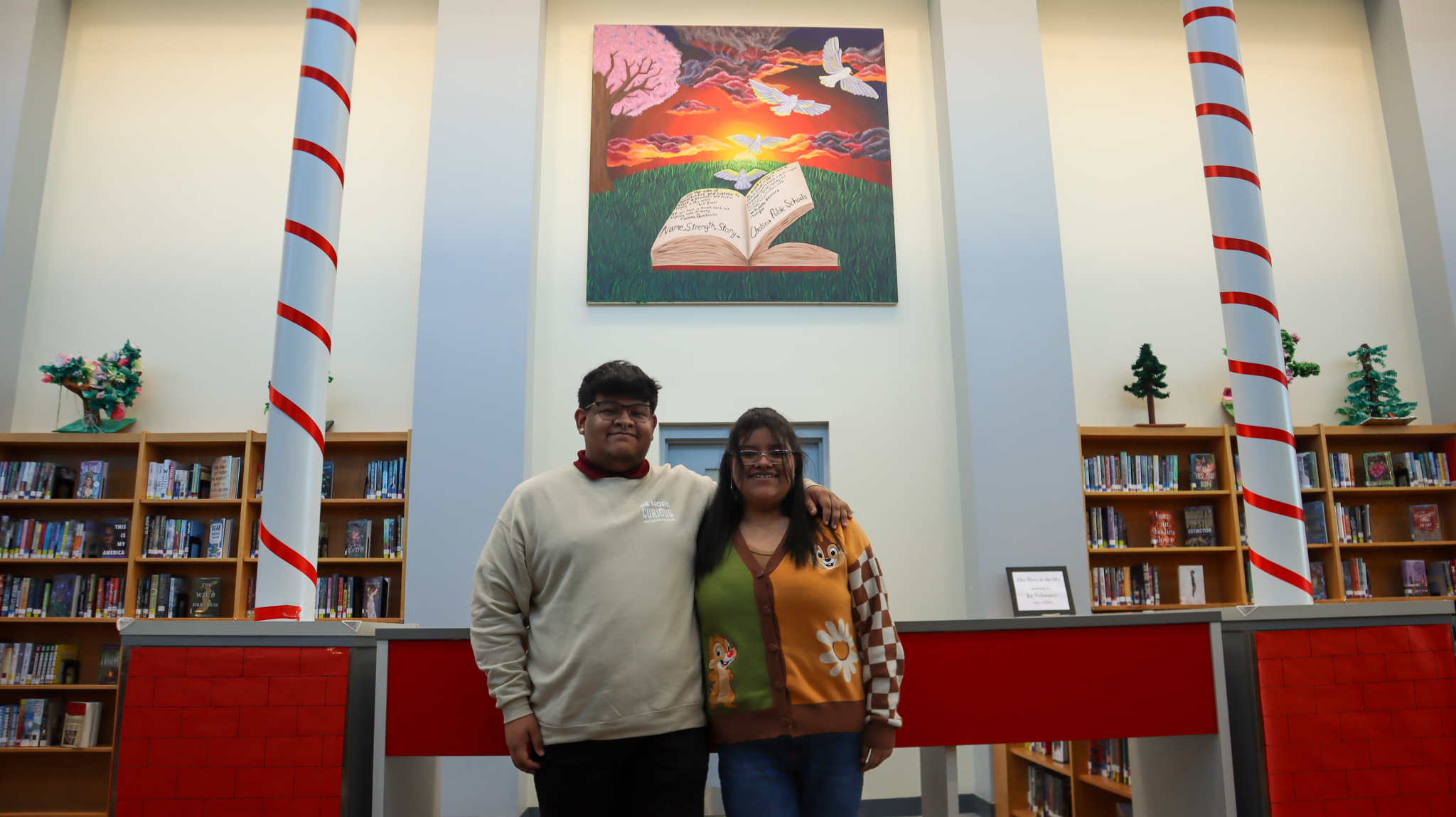 Jasmine (Jay) Velasquez pictured with her brother in the CHS Library with her mural in the background.